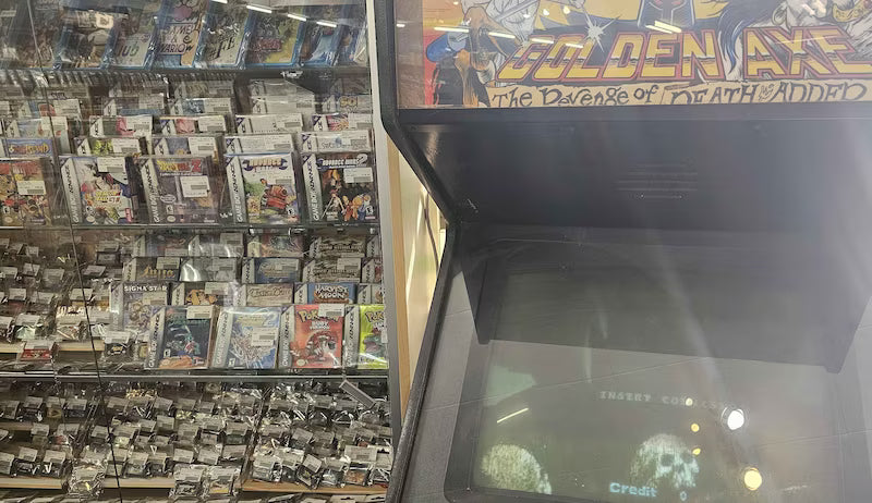 Vintage arcade cabinet for "Golden Axe" with many Game Boy games on the left.