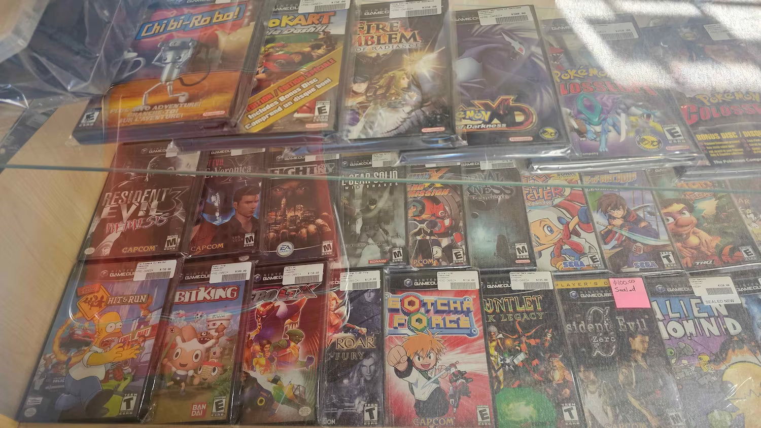 Two layers of Game Cube games sitting inside of a cabinet.